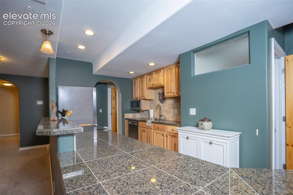 Image 32 of 50: A full kitchen in the basement including a full elect range/oven, refrig, d