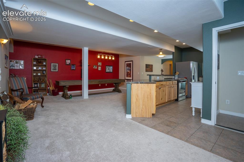 Image 33 of 50: A look from the sitting area into the kitchen and dining area of the baseme