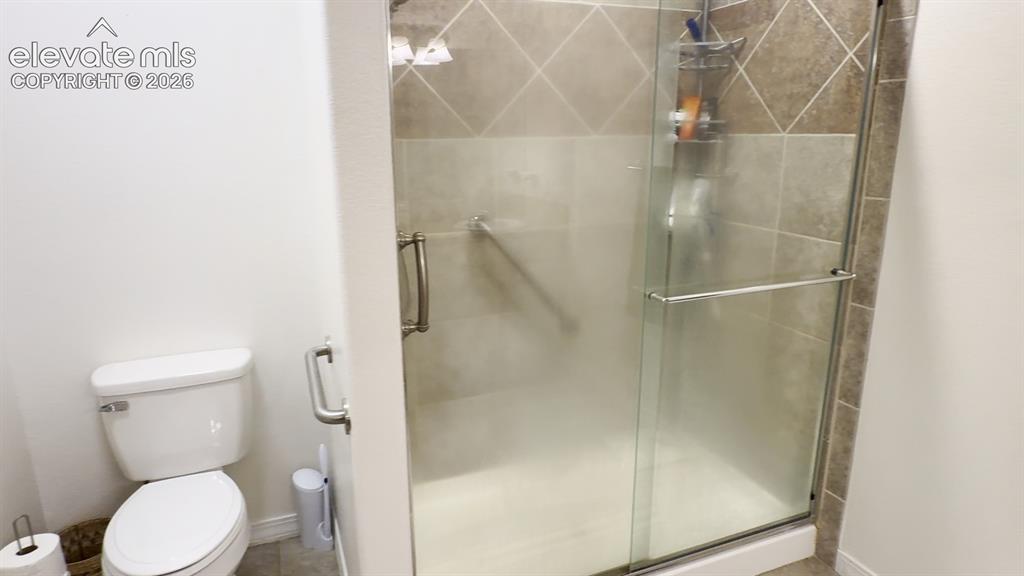 Image 36 of 50: The 2nd Primary bathroom shows the oversized tiled shower with hand rails, 