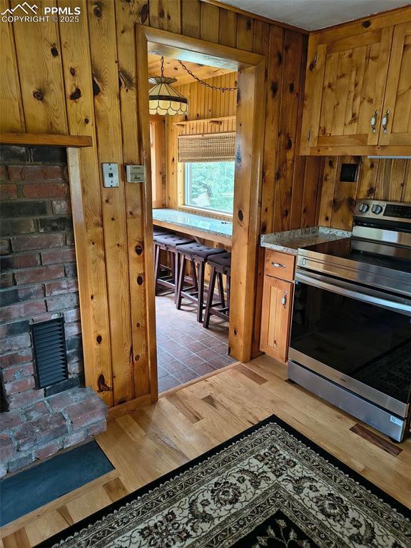 Image 13 of 20: Kitchen featuring electric range, brown cabinets, and light wood finished f
