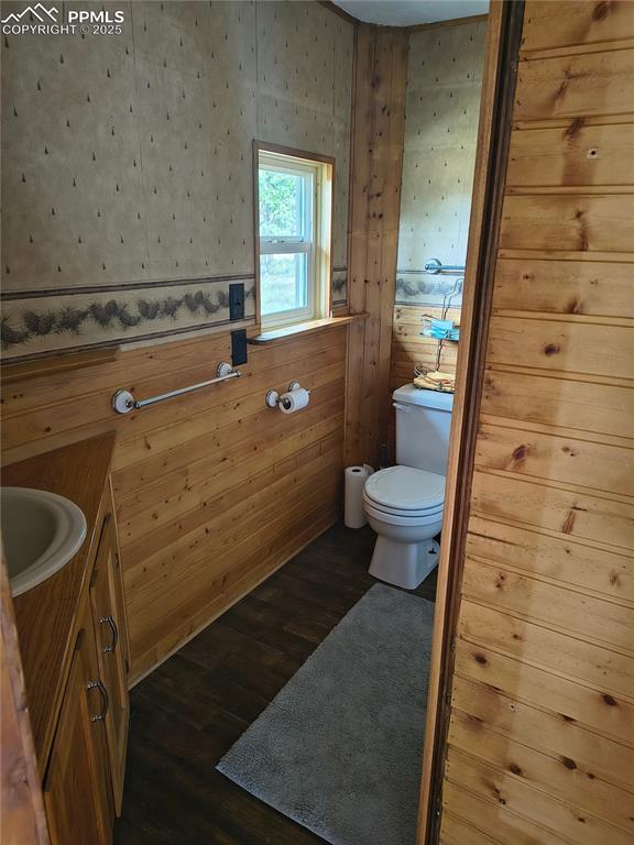 Image 21 of 27: Half bathroom featuring vanity, dark wood-style flooring, and wooden walls