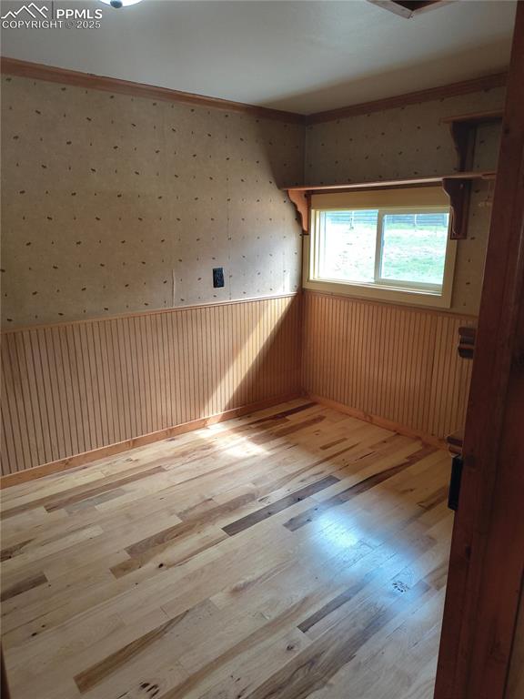 Image 24 of 27: Additional living space with light wood-style flooring and wallpapered wall