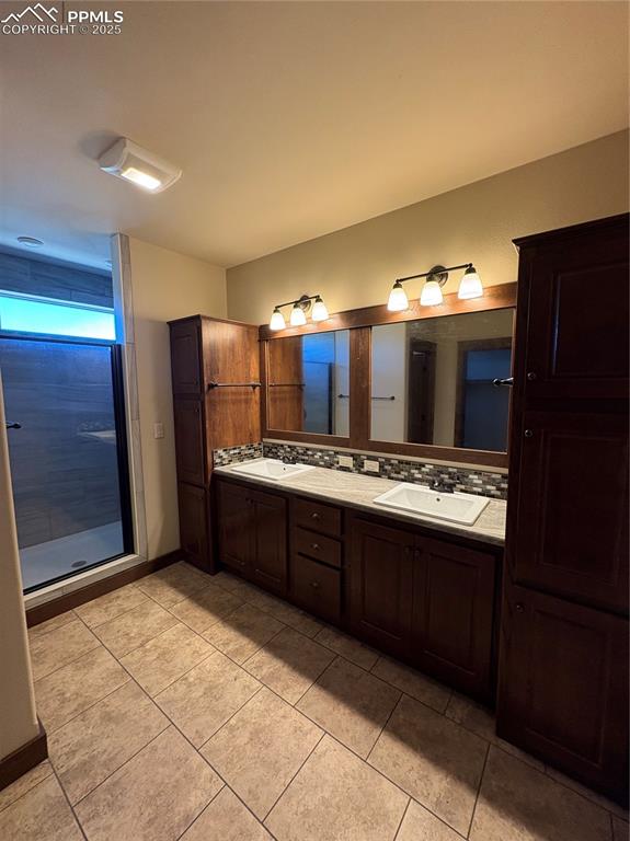 Image 10 of 32: Full bathroom with double vanity, decorative backsplash, a stall shower, an