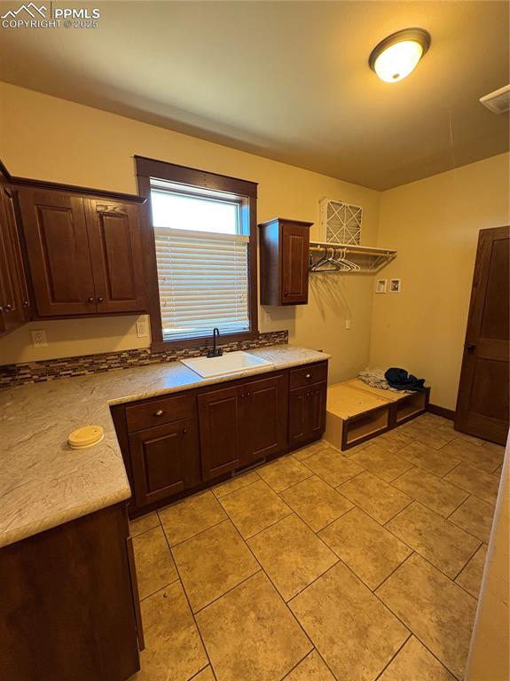 Image 13 of 31: Kitchen featuring dark brown cabinetry, light tile patterned flooring, and