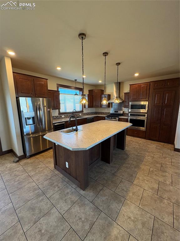 Image 18 of 31: Kitchen featuring refrigerator, dark brown cabinets, wall oven, an island w