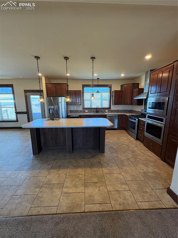 Image 19 of 31: Kitchen with dark brown cabinetry, light tile patterned floors, a center is