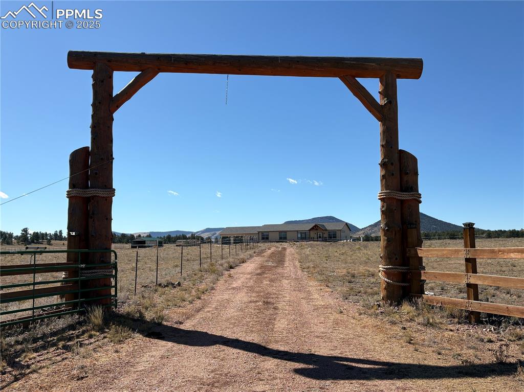 Image 2 of 32: View of dirt / gravel driveway with a gated entry, a view of rural / pastor