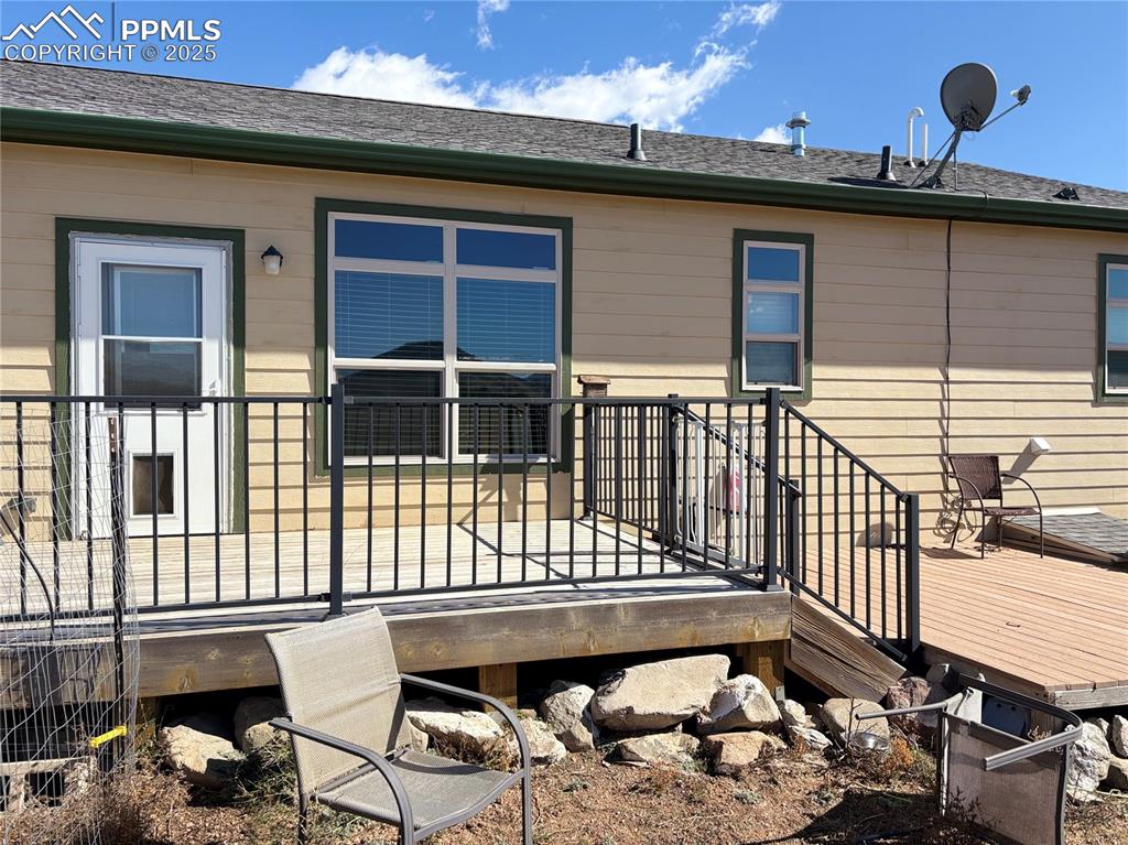 Image 4 of 32: Rear view of property featuring a wooden deck and roof with shingles