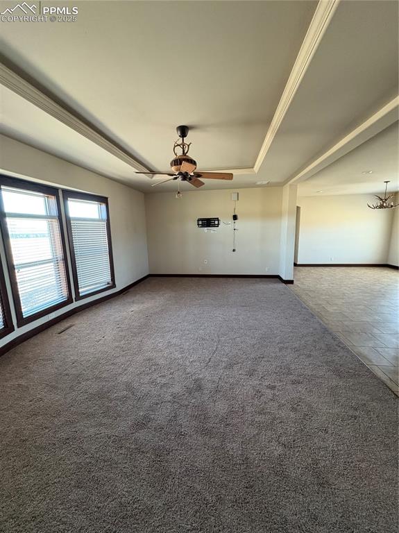 Image 7 of 32: Unfurnished living room with a tray ceiling, carpet flooring, ceiling fan, 