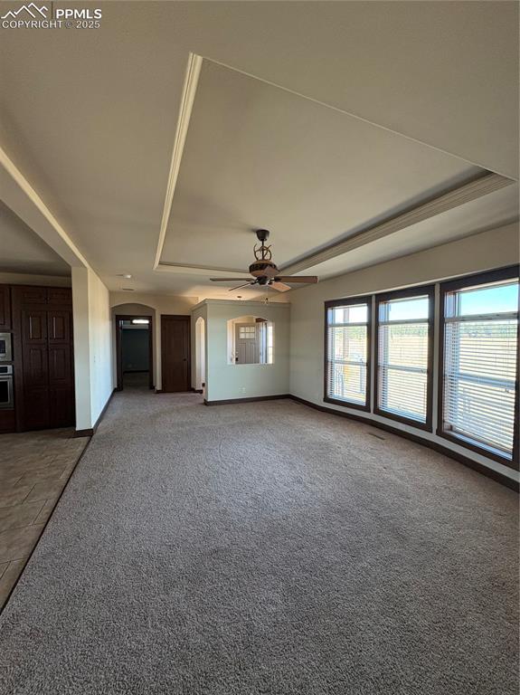 Image 8 of 32: Unfurnished living room featuring a raised ceiling, carpet floors, and ceil