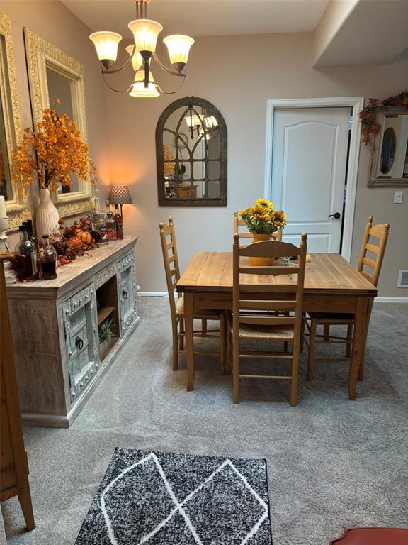 Image 10 of 24: Dining space with light colored carpet and a chandelier