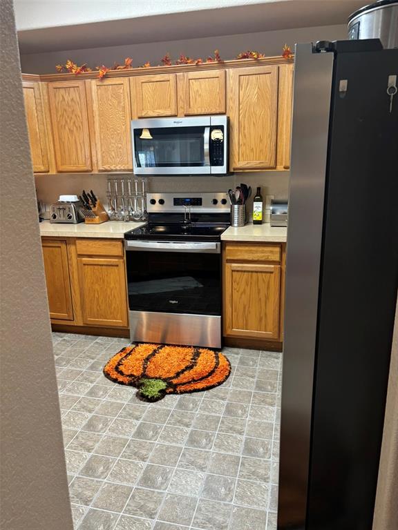Image 13 of 24: Kitchen with stainless steel appliances and light countertops
