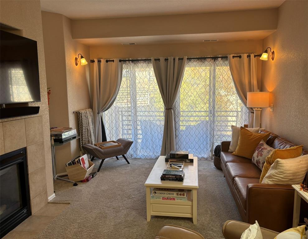 Image 15 of 24: Living room featuring a textured wall, a fireplace, healthy amount of natur