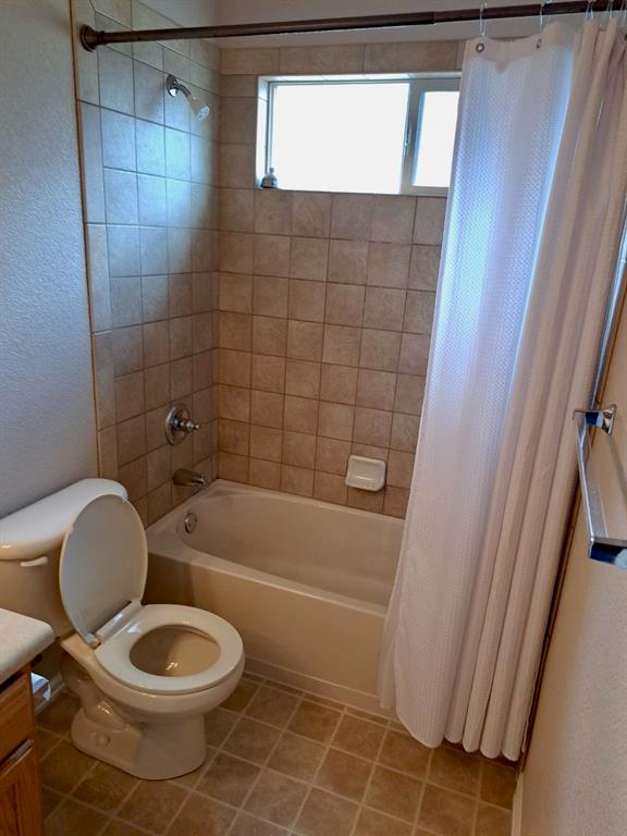 Image 21 of 24: Bathroom featuring shower / bath combo with shower curtain, vanity, a textu