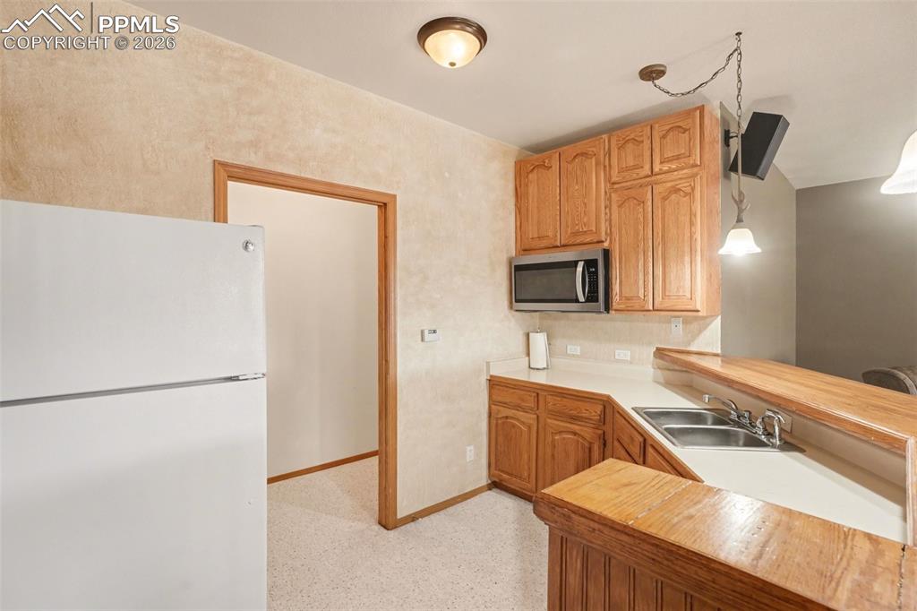 Image 29 of 39: Wet bar with microwave and bar height seating. (refrigerator excluded)