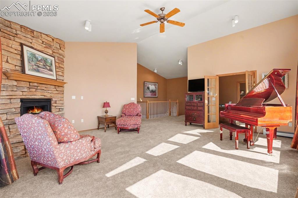 Image 5 of 39: Living area featuring ceiling fan, vaulted ceiling, light carpet, and a fir