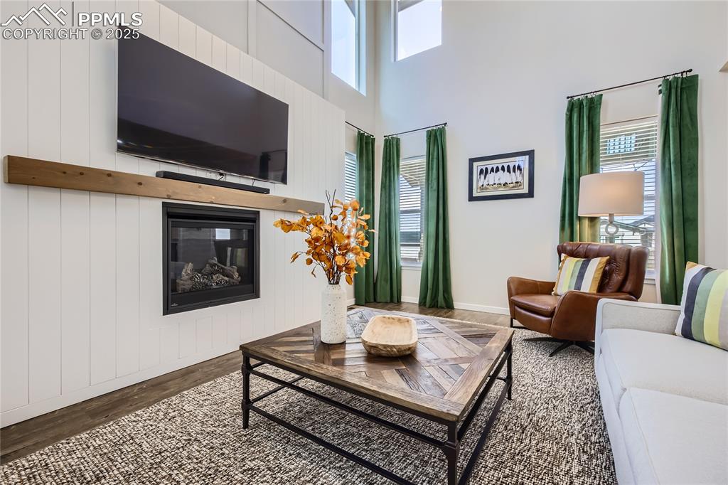 Image 6 of 39: Living room with a glass covered fireplace, a high ceiling, and wood finish