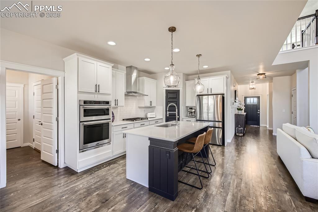 Image 7 of 39: Kitchen featuring tasteful backsplash, wall chimney range hood, stainless s