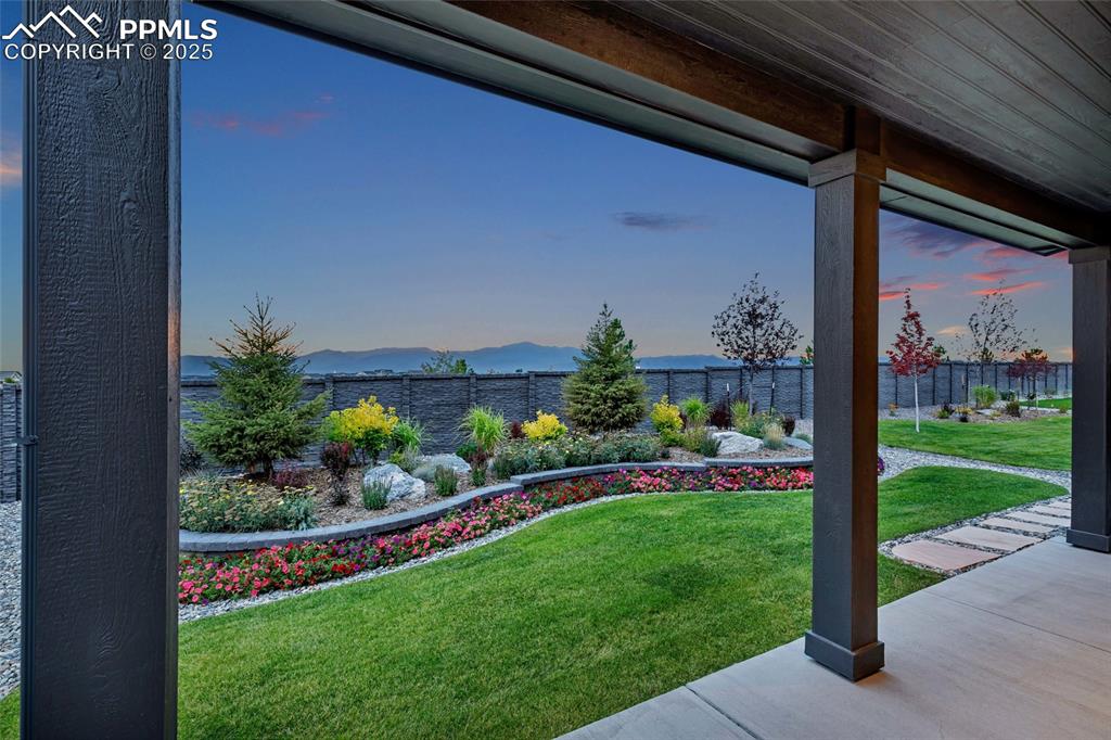 Image 45 of 47: Yard at dusk with a fenced backyard, a mountain view, and covered porch
