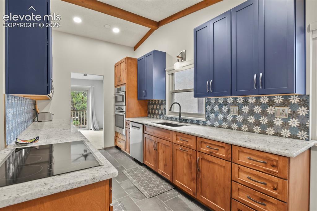 Image 13 of 50: Kitchen featuring vaulted ceilings with exposed wood beams, dual-tone cabin