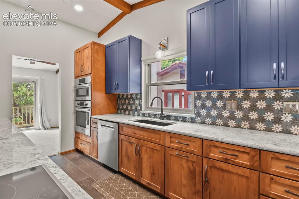 Image 15 of 50: Kitchen featuring two-tone cabinetry with blue upper cabinets and wood-fini