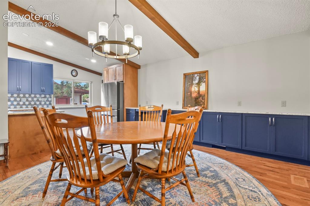 Image 17 of 50: Dining area featuring a contemporary chandelier, exposed wood ceiling beams