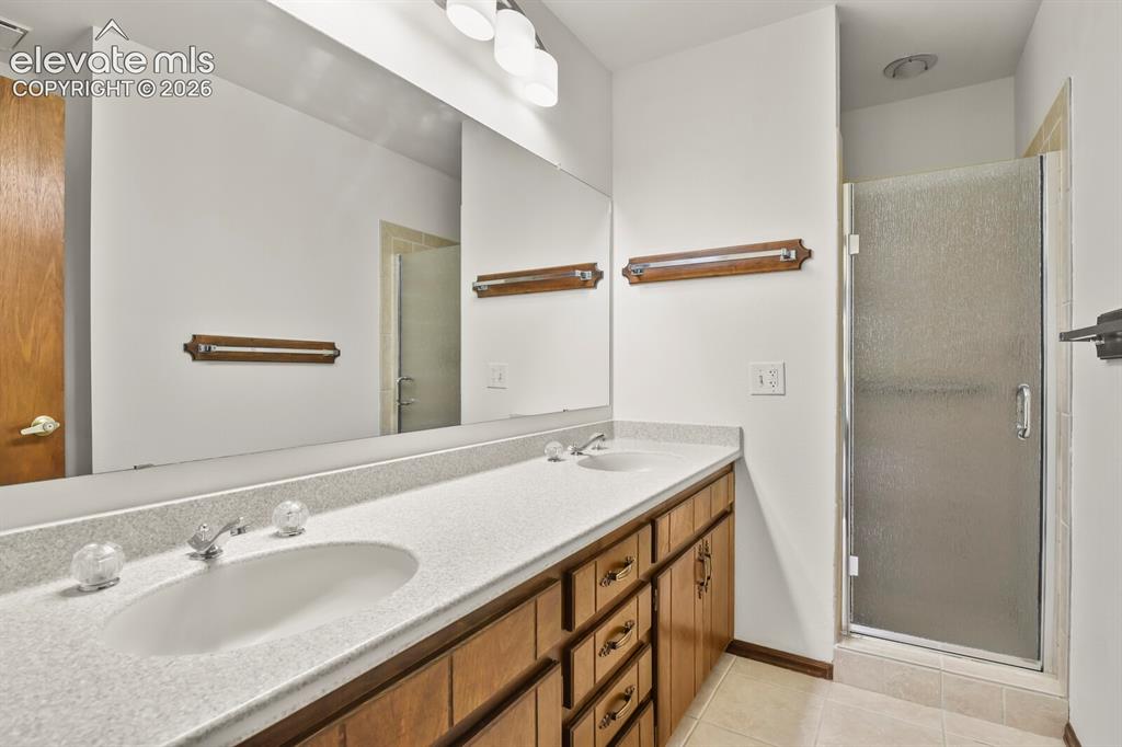 Image 21 of 50: Bathroom featuring a dual-sink vanity with wood-finish cabinetry, a large w