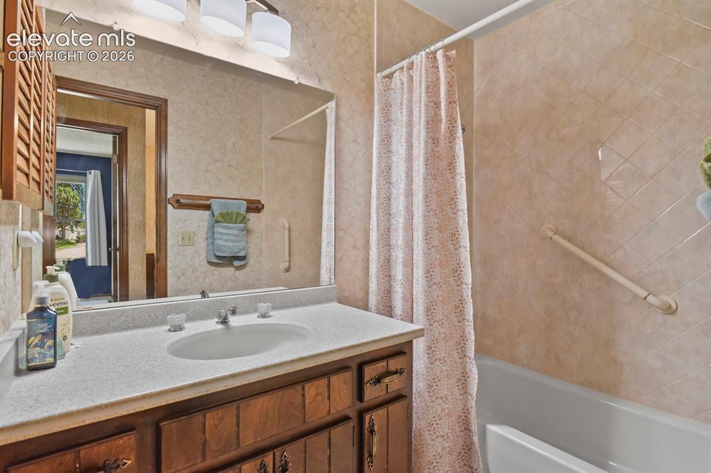 Image 24 of 50: Bathroom featuring a wood-finish vanity with a built-in sink, a wall-mounte