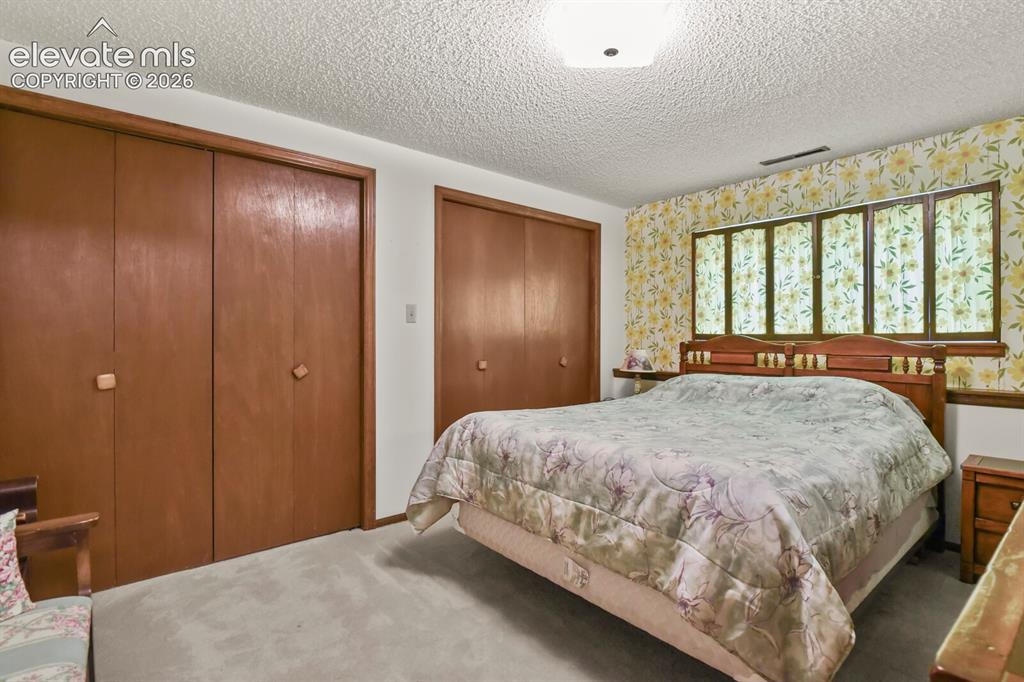 Image 34 of 50: Bedroom featuring a large window with floral wallpaper surround, two sets o
