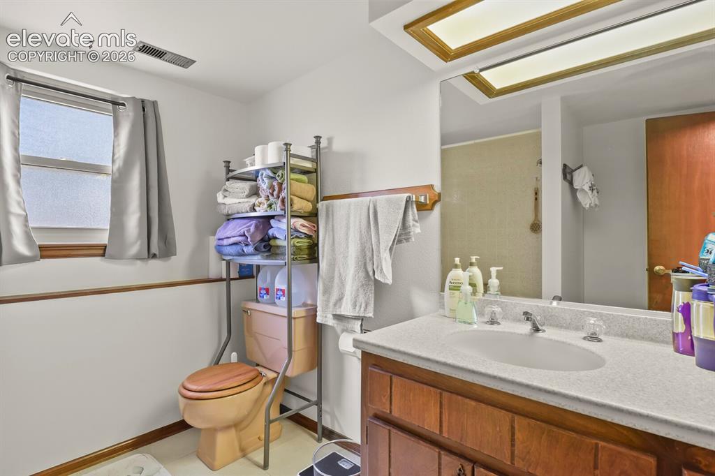 Image 36 of 50: Bathroom featuring a wood-finish vanity with a light-colored countertop and
