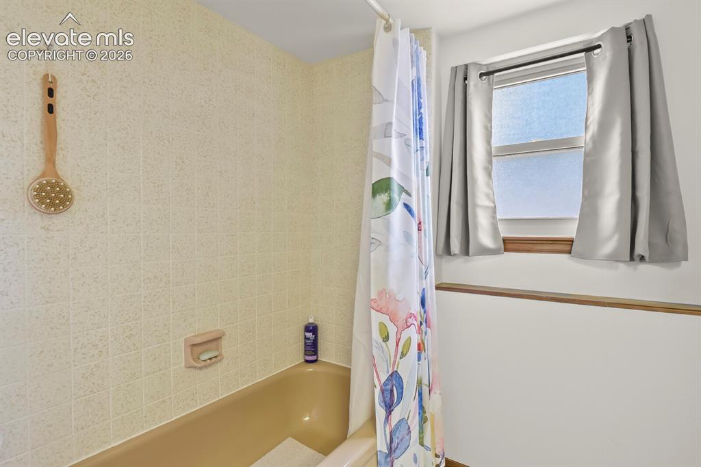 Image 37 of 50: Bathtub featuring light-colored tile surround, integrated soap dish, and a