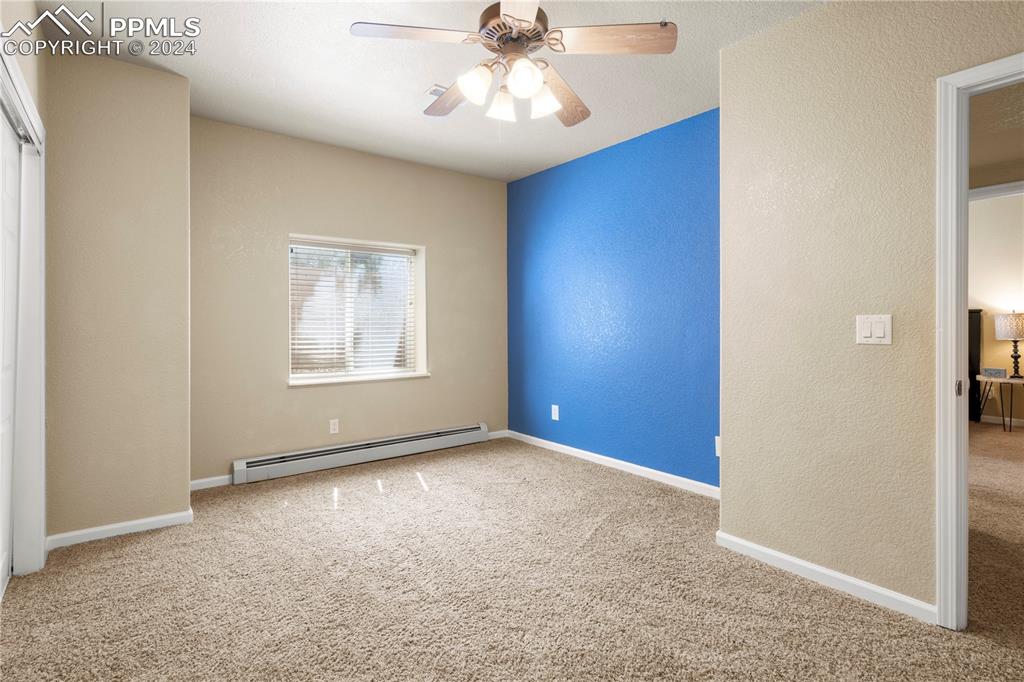 Image 28 of 39: Carpeted empty room with a baseboard radiator and ceiling fan