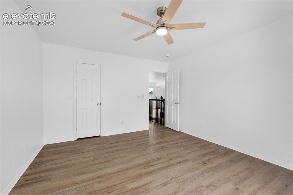 Image 27 of 35: Spacious room featuring wood-finish flooring and a contemporary ceiling fan