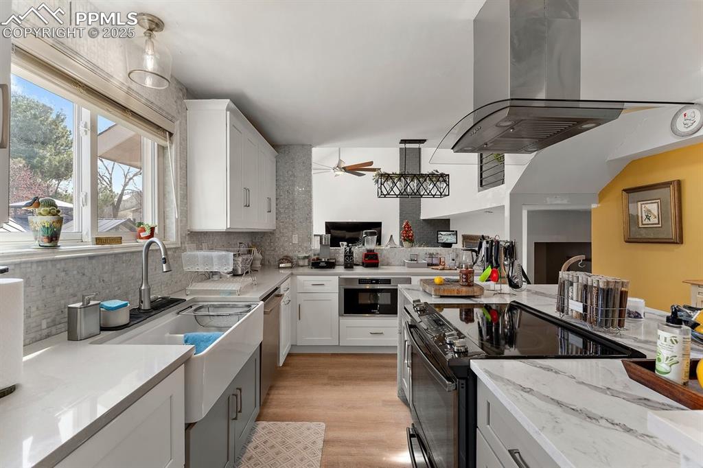 Image 14 of 41: Kitchen featuring island exhaust hood, stainless steel appliances, backspla