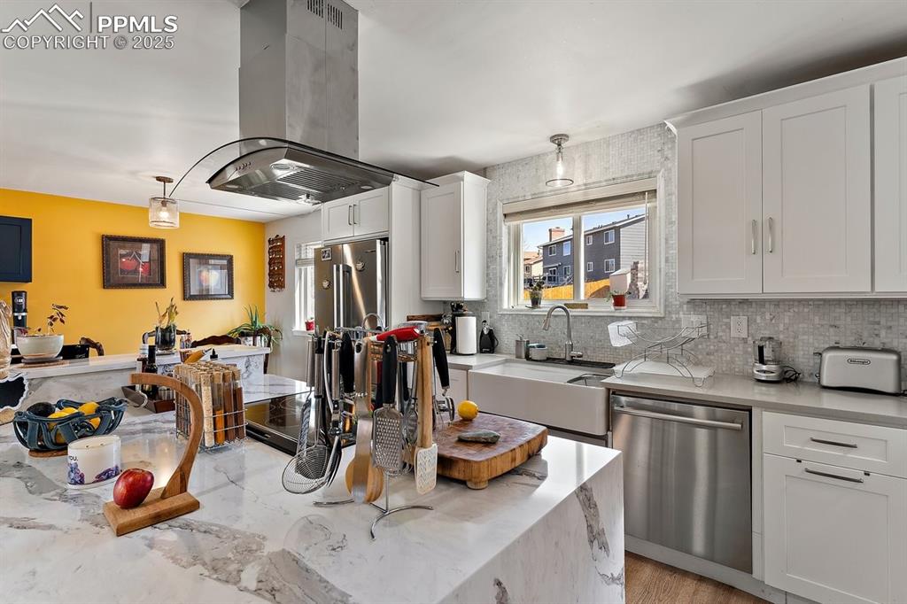 Image 17 of 41: Kitchen featuring island exhaust hood, stainless steel appliances, decorati