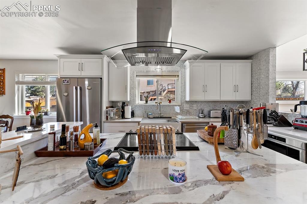 Image 18 of 41: Kitchen with island exhaust hood, healthy amount of natural light, tasteful