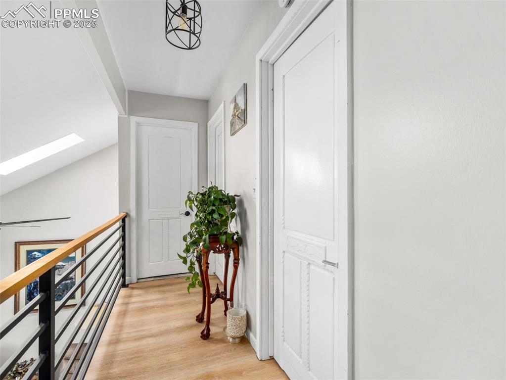 Image 22 of 41: Hallway with a skylight, light wood-style floors, and an upstairs landing