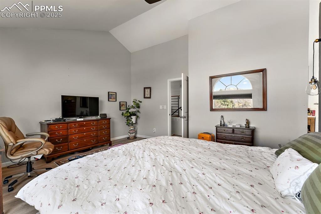 Image 26 of 41: Bedroom featuring high vaulted ceiling and wood finished floors