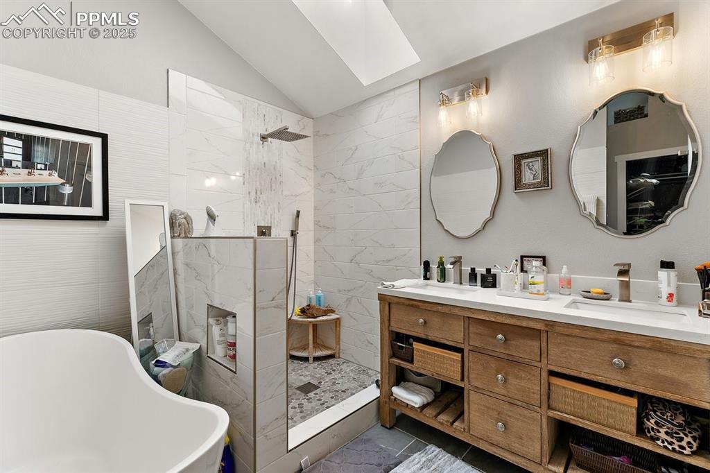 Image 27 of 41: Full bath featuring walk in shower, double vanity, vaulted ceiling, a soaki