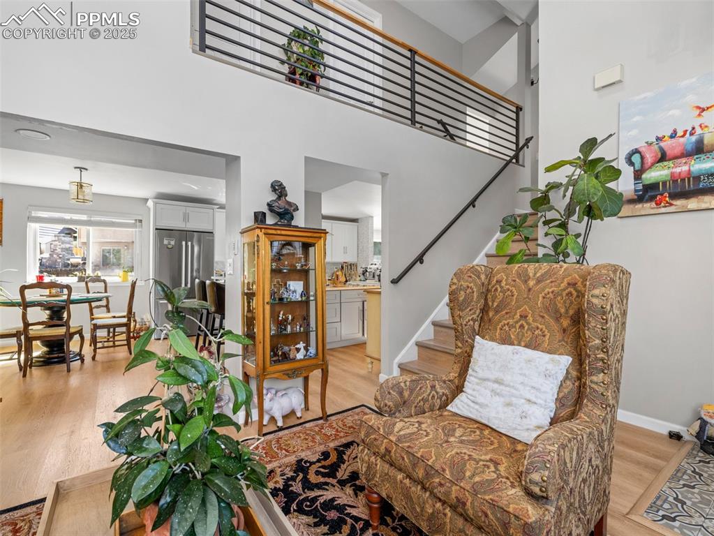 Image 8 of 41: Living area with stairway, light wood-type flooring, and a towering ceiling