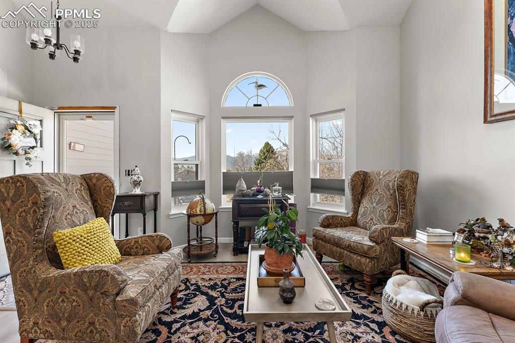 Image 9 of 41: Living area with a towering ceiling, a chandelier, and wood finished floors