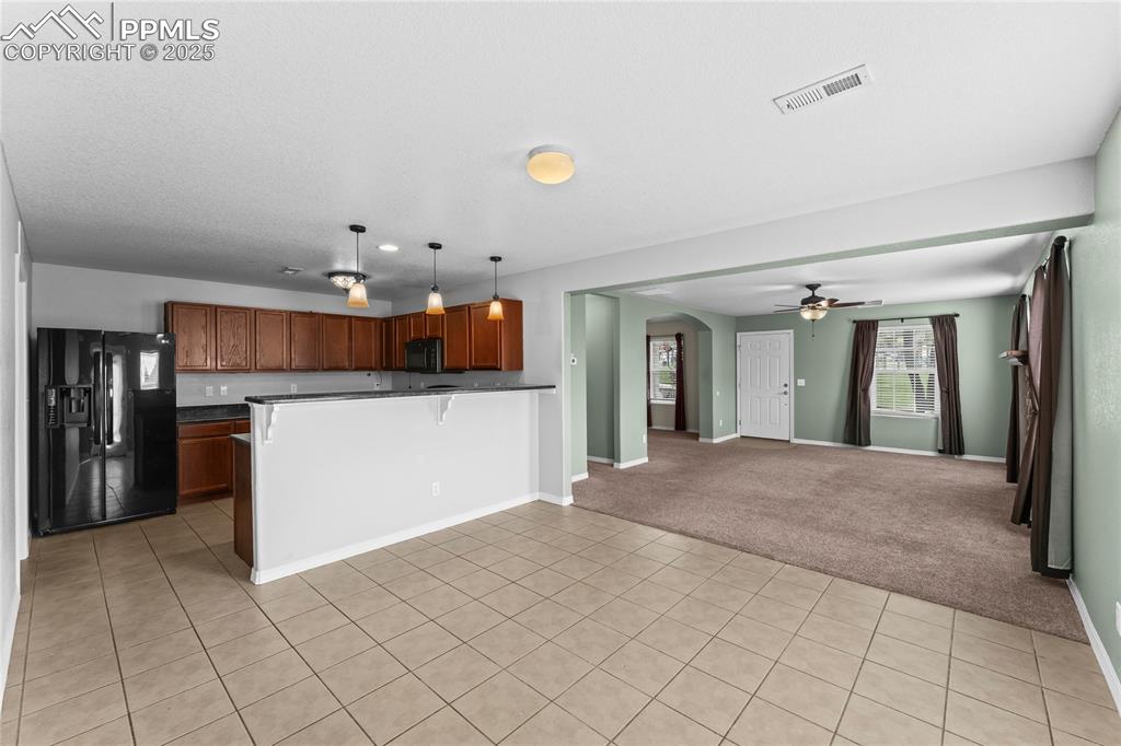 Image 11 of 30: Kitchen with arched walkways, open floor plan, black appliances, decorative