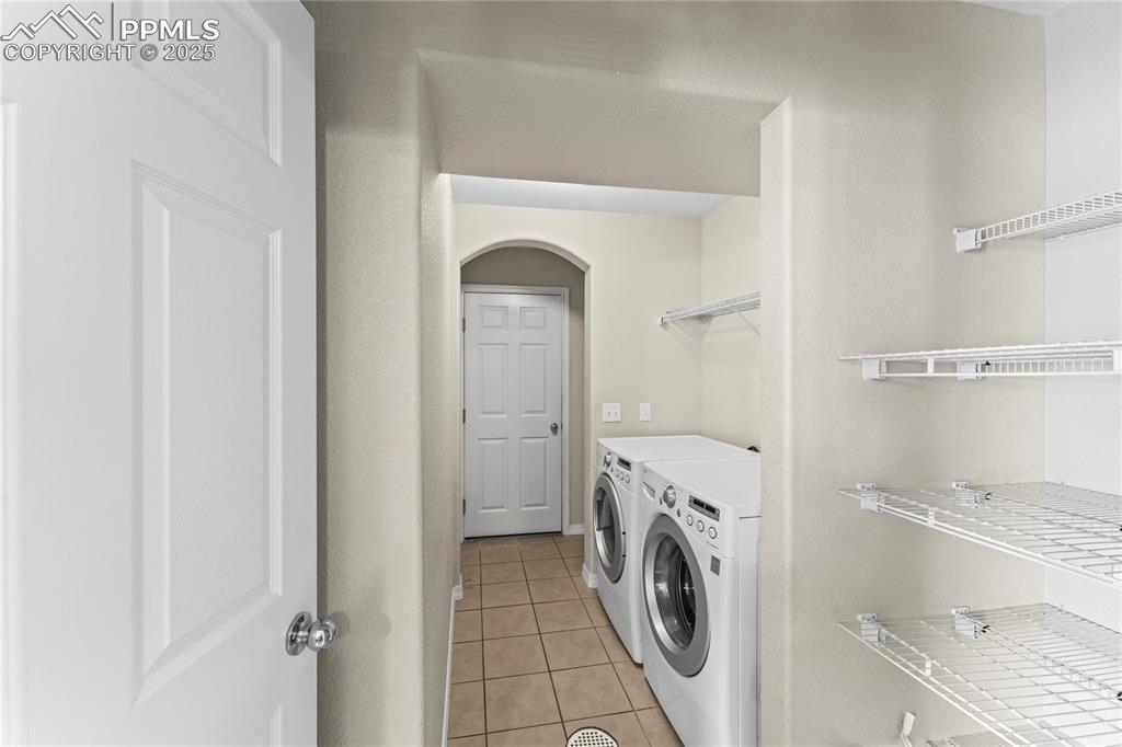 Image 14 of 30: Washroom featuring light tile patterned floors, separate washer and dryer, 