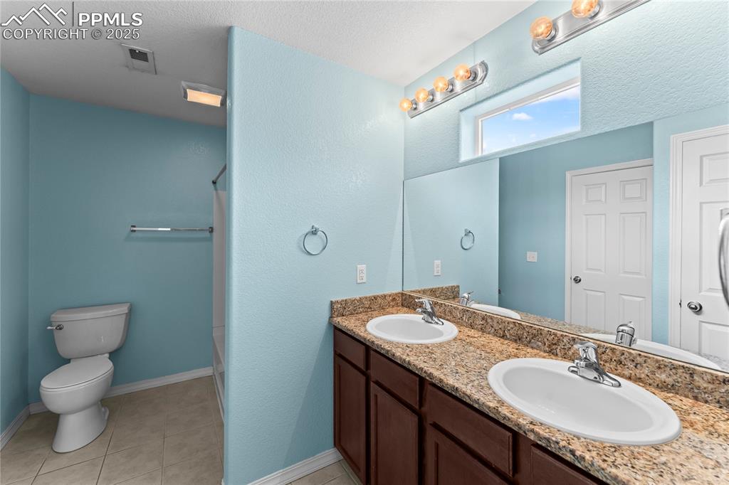 Image 18 of 30: Bathroom with light tile patterned flooring, double vanity, a shower stall,