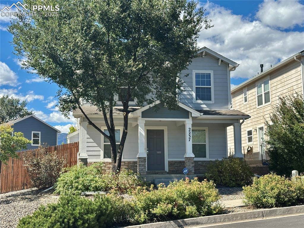 Image 2 of 30: View of front of home with covered porch and stone siding