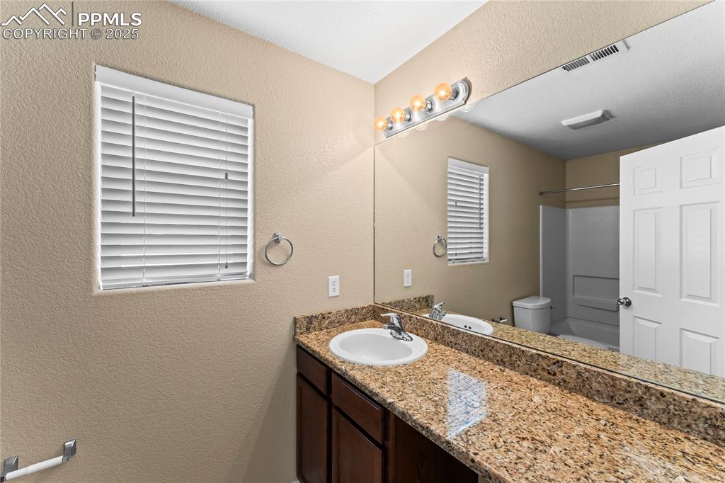 Image 21 of 30: Full bathroom featuring a textured wall, vanity, and shower / bath combinat