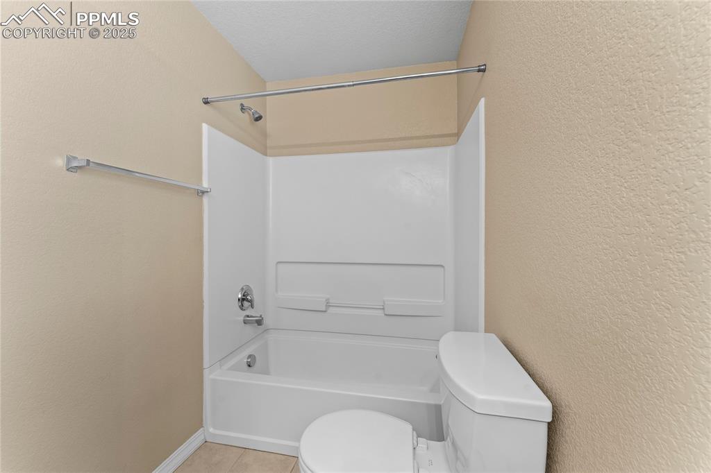 Image 22 of 30: Bathroom with shower / tub combination, a textured wall, and light tile pat