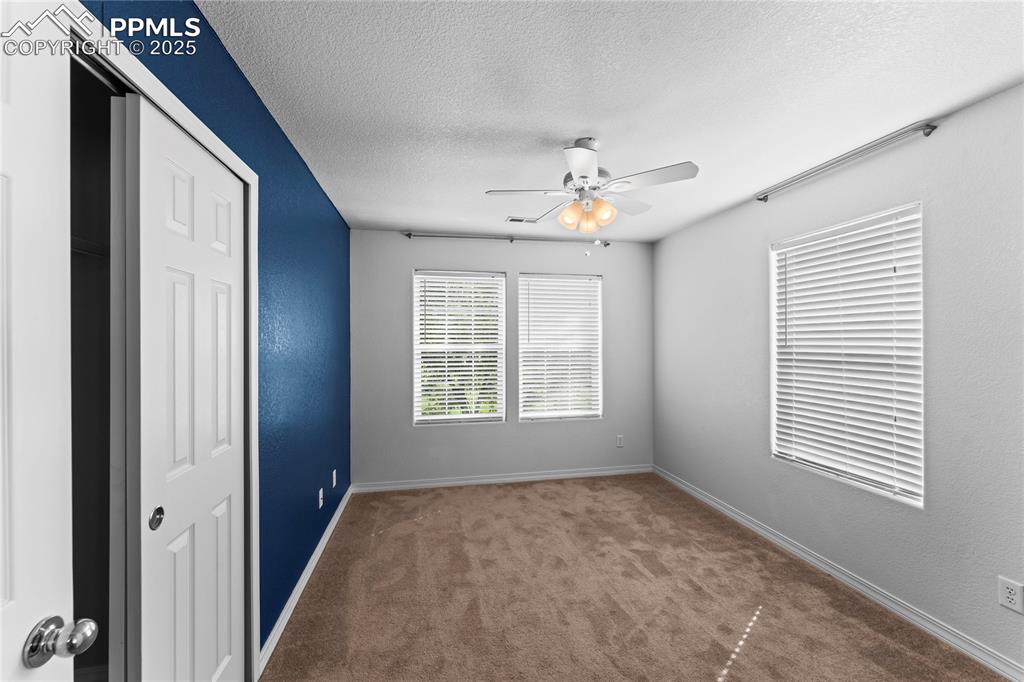 Image 25 of 30: Spare room with a textured ceiling, carpet, ceiling fan, and a textured wal