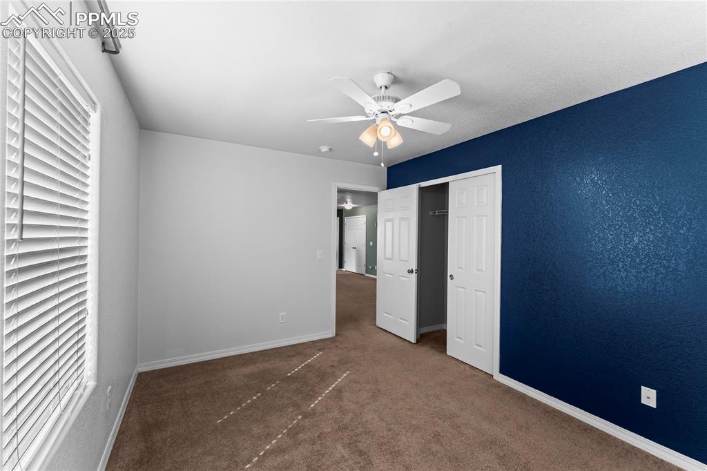 Image 26 of 30: Unfurnished bedroom featuring dark colored carpet, ceiling fan, and a close
