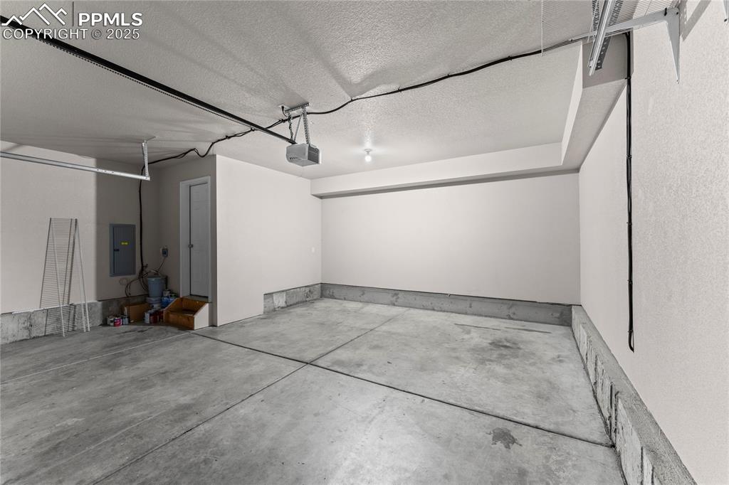Image 29 of 30: Garage with electric panel and a garage door opener